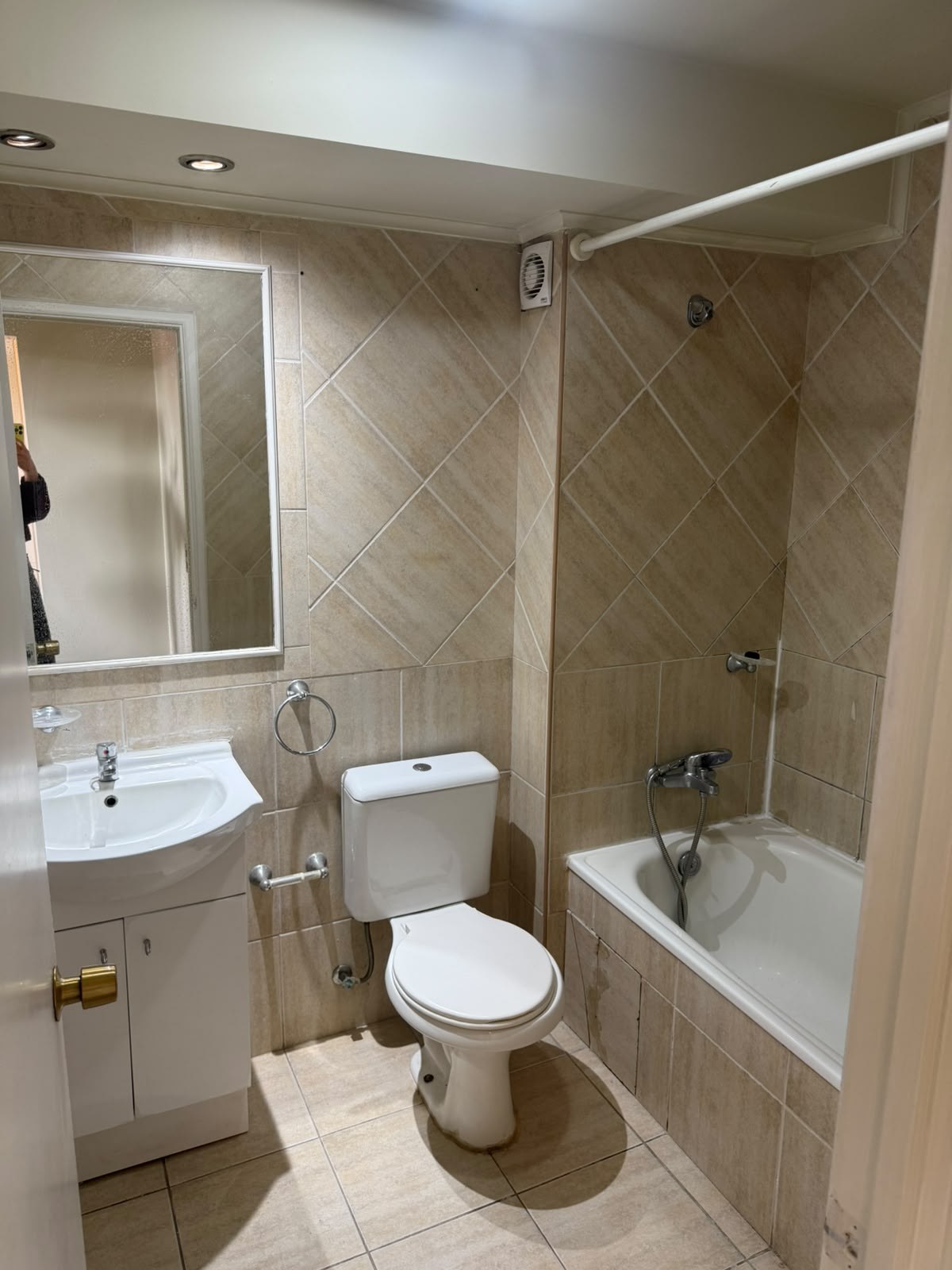 Baño completo con tina, vanitorio blanco y paredes con cerámica