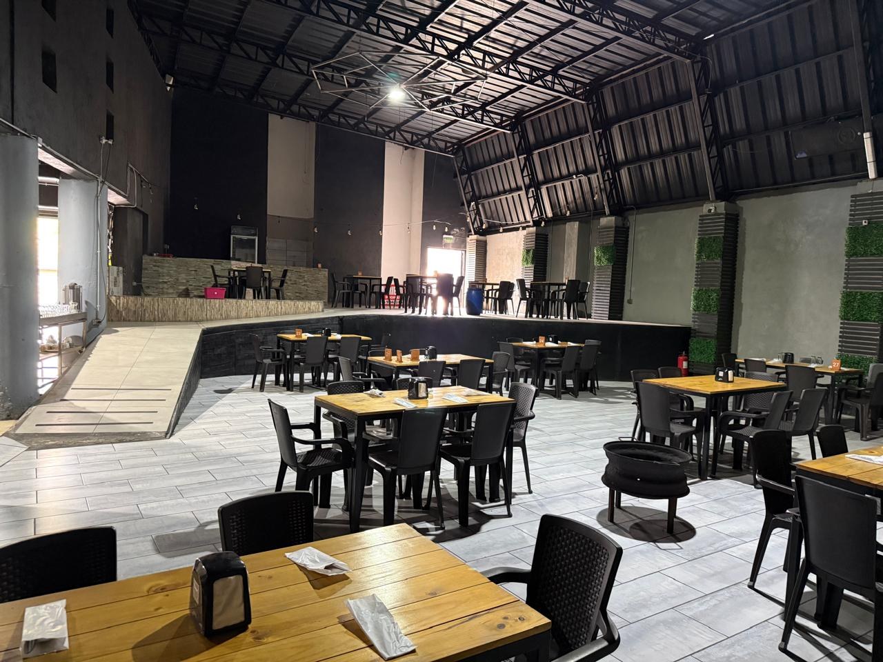 Área de mesas en salón con vista hacia escenario elevado