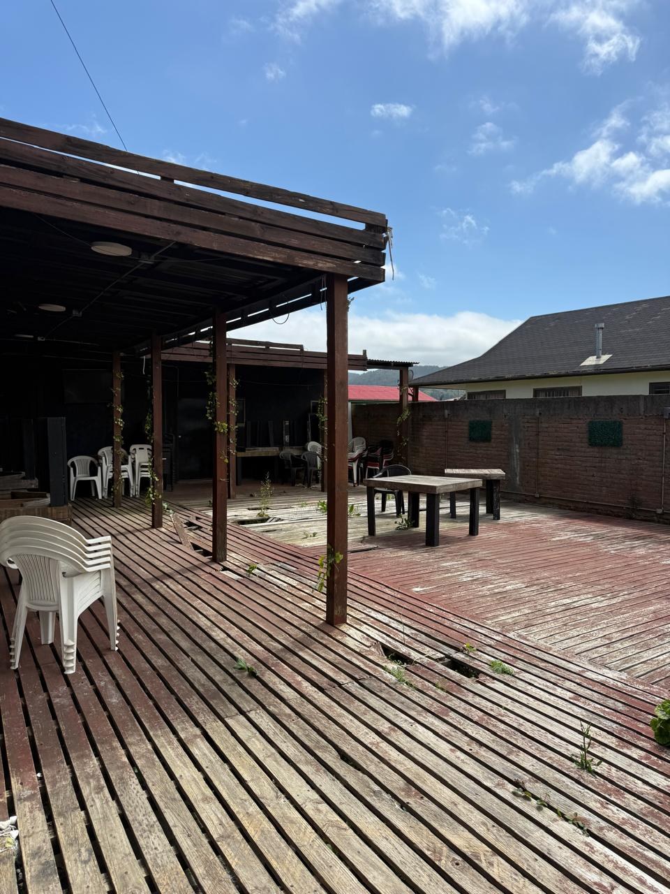 Terraza exterior con piso de madera y mesas al aire libre